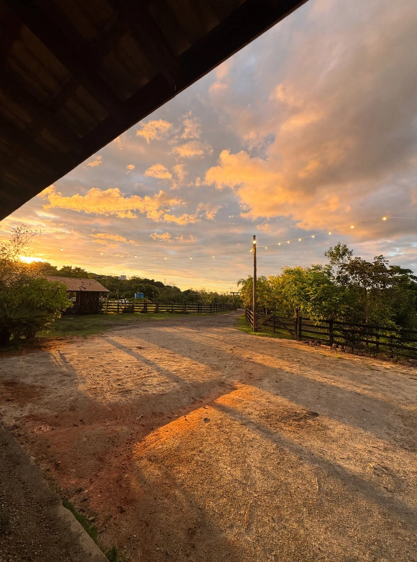 Vista do estacionamento do sítio ao entardecer, visto de baixo do telhado do salão